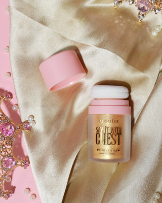 A container of P.Louise Say It With Chest Loose Body Glitter in Golden Era shade, with the cap removed, displayed on a surface with a reflective and sparkling appearance.
