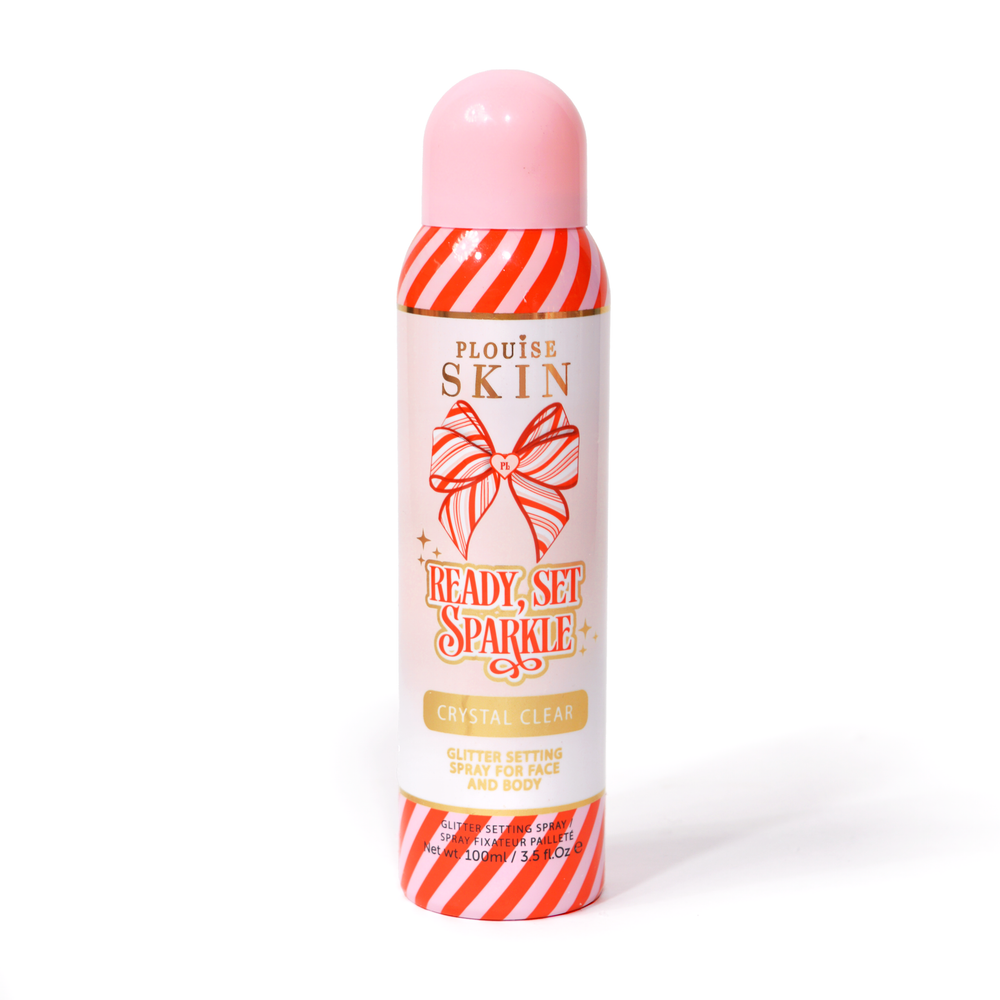 A bottle of P. Louise Ready Set Sparkle Christmas Glitter Setting Spray with red and pink stripes on the bottle and a red and pink striped bow against a white background