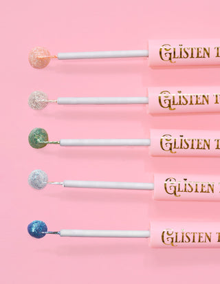 5 P.Louise Glisten To Your Heart glitter eyeliners lined up with a drip of the product on the end against a pink background