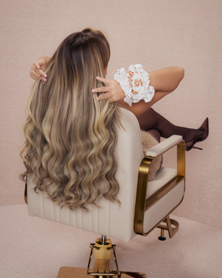 Woman with styled hair sitting in a salon chair with an arm full of teddy hair scrunchies